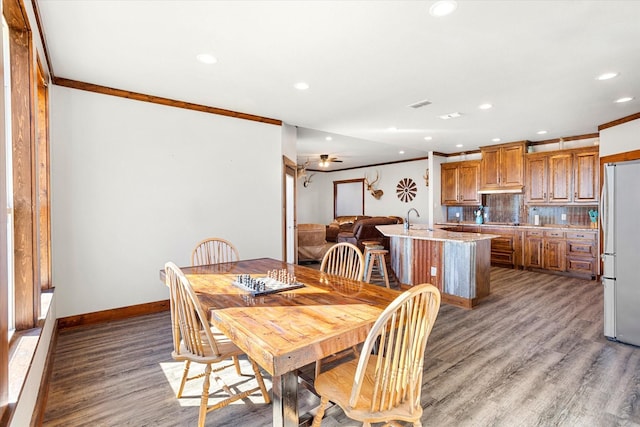 dining room featuring sink, ornamental molding, and light wood-type flooring