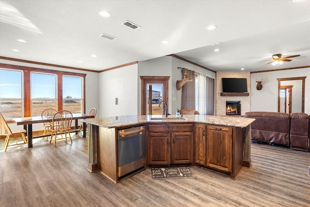 kitchen with dishwasher, ceiling fan, sink, and a kitchen island with sink