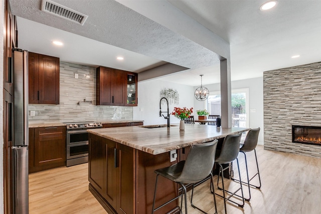 kitchen with a kitchen breakfast bar, sink, a tile fireplace, electric stove, and a center island with sink