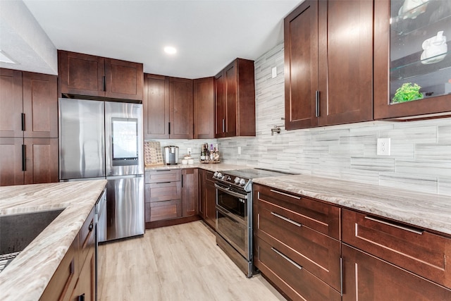 kitchen with decorative backsplash, appliances with stainless steel finishes, light hardwood / wood-style floors, and light stone counters