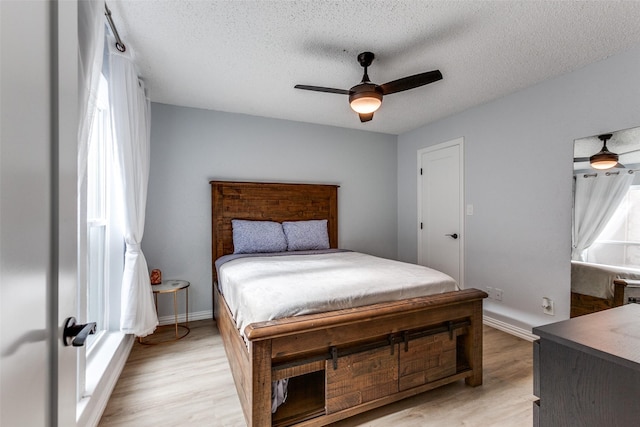 bedroom with a textured ceiling, light hardwood / wood-style floors, and ceiling fan