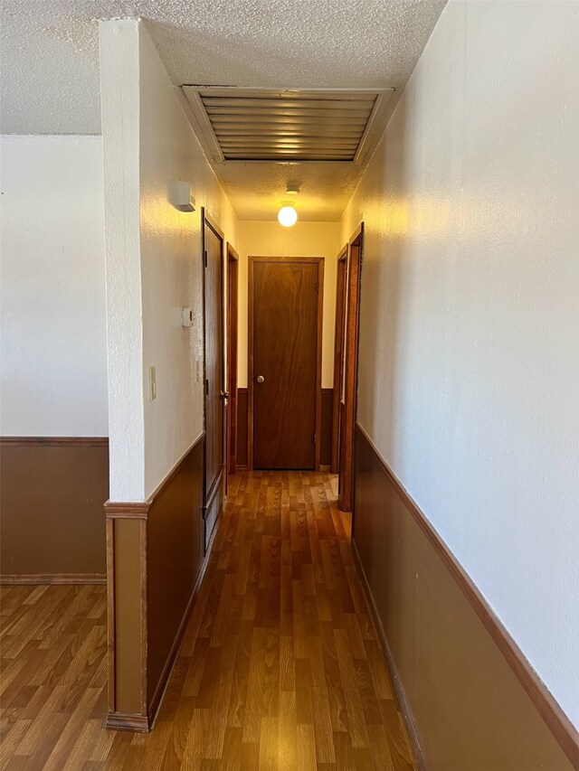 hall featuring a textured ceiling and dark wood-type flooring