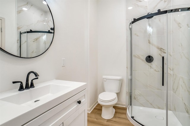 bathroom with hardwood / wood-style floors, vanity, toilet, and a shower with door