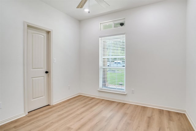 empty room featuring a wealth of natural light, ceiling fan, and light hardwood / wood-style floors