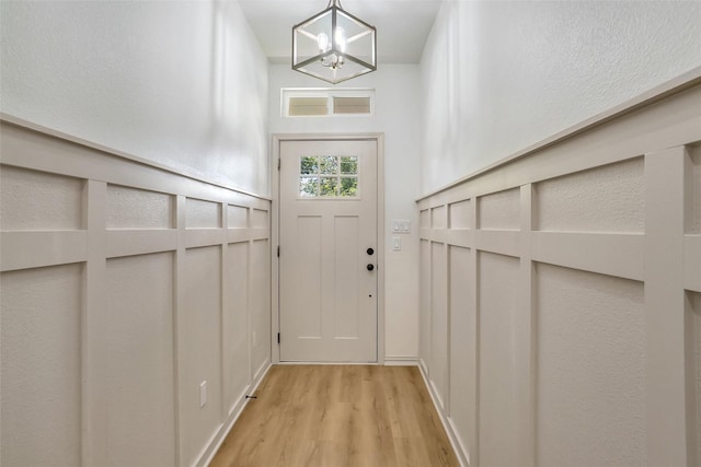 doorway to outside with a chandelier and light hardwood / wood-style flooring