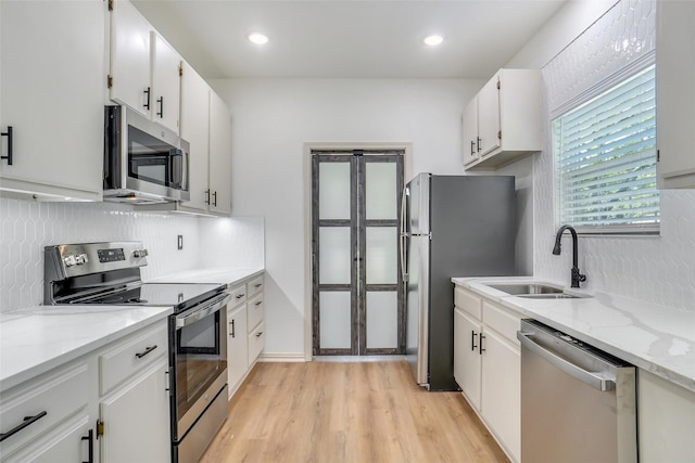 kitchen featuring light stone countertops, white cabinetry, sink, and appliances with stainless steel finishes