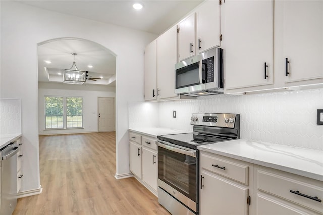 kitchen featuring light stone countertops, stainless steel appliances, tasteful backsplash, light hardwood / wood-style flooring, and white cabinets