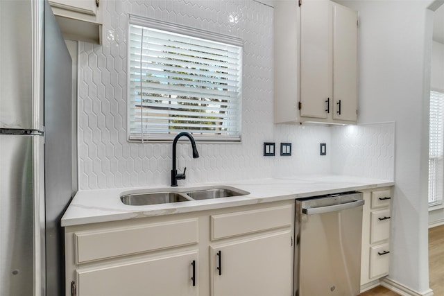 kitchen featuring light stone countertops, appliances with stainless steel finishes, white cabinetry, and sink