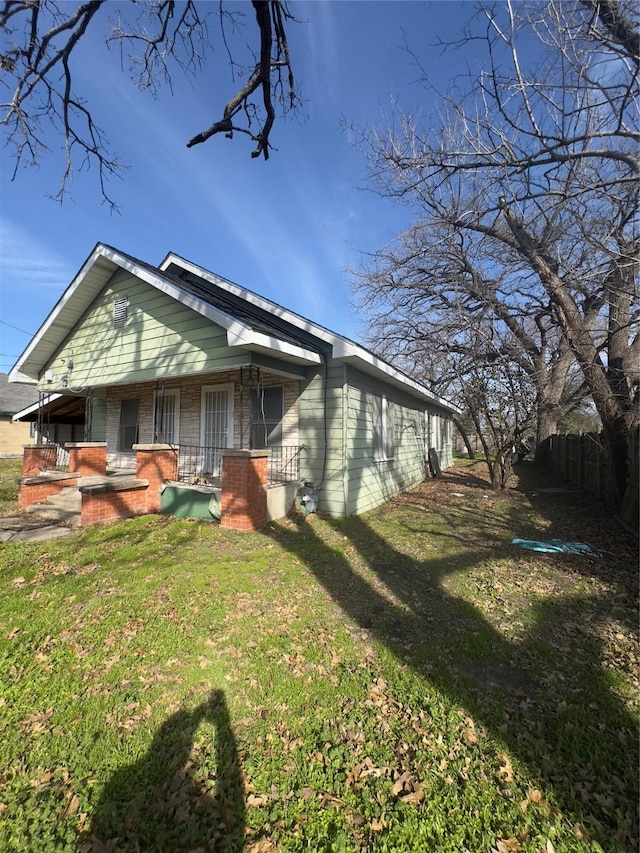 view of side of home featuring a lawn and a porch