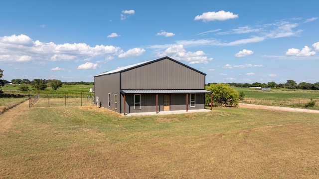 rear view of property with a yard, a rural view, and an outdoor structure