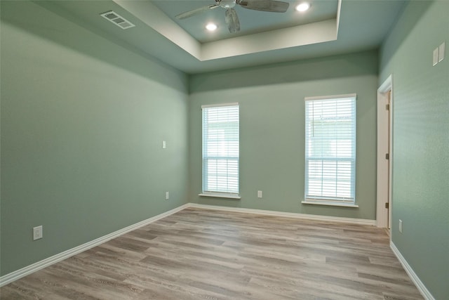 empty room featuring a tray ceiling, a wealth of natural light, and ceiling fan