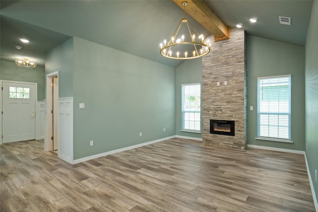 unfurnished living room with beamed ceiling, wood-type flooring, an inviting chandelier, and a fireplace