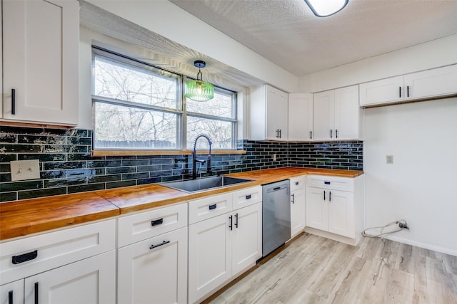 kitchen with sink, white cabinets, dishwasher, and wood counters