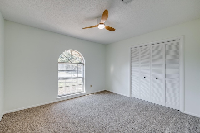 unfurnished bedroom featuring a closet, carpet floors, ceiling fan, and a textured ceiling