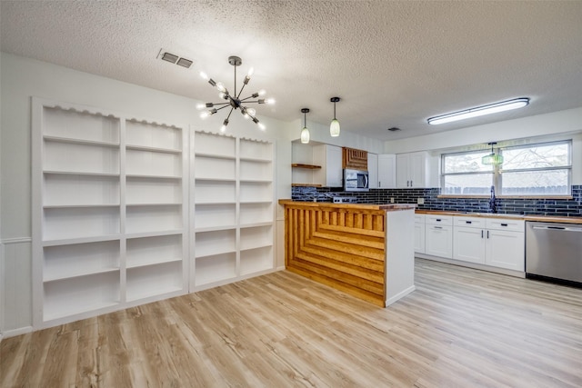 kitchen with butcher block counters, white cabinetry, a chandelier, pendant lighting, and appliances with stainless steel finishes