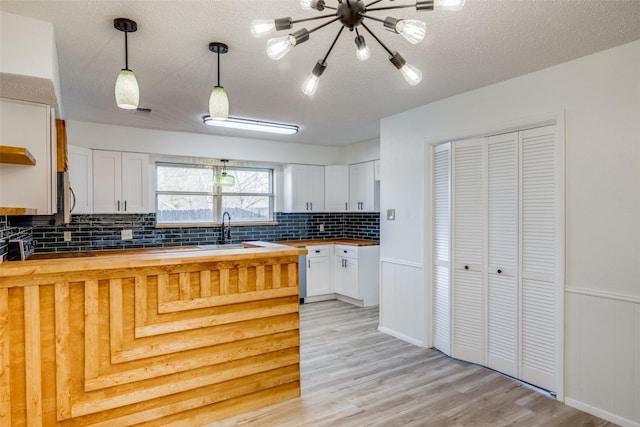 kitchen featuring sink, white cabinets, decorative light fixtures, a textured ceiling, and wooden counters