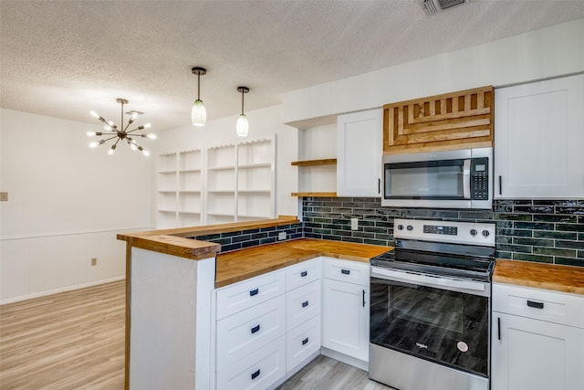 kitchen with appliances with stainless steel finishes, white cabinetry, and butcher block counters