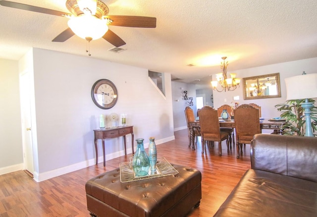 dining area with ceiling fan with notable chandelier, a textured ceiling, and hardwood / wood-style floors