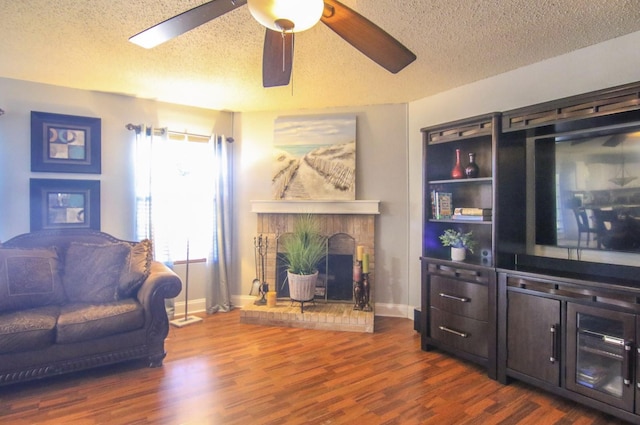 living room with a textured ceiling, ceiling fan, dark hardwood / wood-style floors, and a fireplace