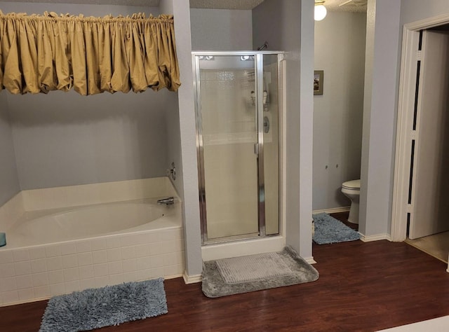 bathroom with plus walk in shower, toilet, a textured ceiling, and wood-type flooring