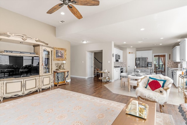 living room with hardwood / wood-style flooring, ceiling fan, and sink