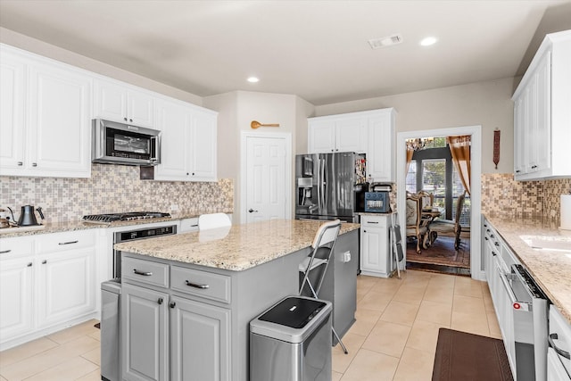 kitchen featuring white cabinets, backsplash, a kitchen island, and stainless steel appliances