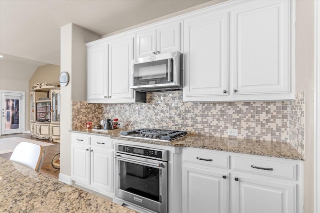 kitchen featuring white cabinets, light stone counters, backsplash, and appliances with stainless steel finishes