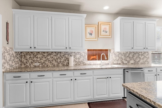 kitchen featuring light stone counters, white cabinetry, sink, and tasteful backsplash