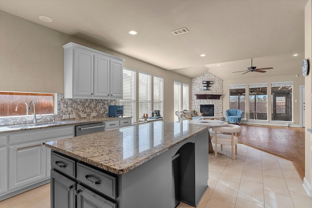 kitchen featuring tasteful backsplash, stainless steel dishwasher, ceiling fan, sink, and a center island