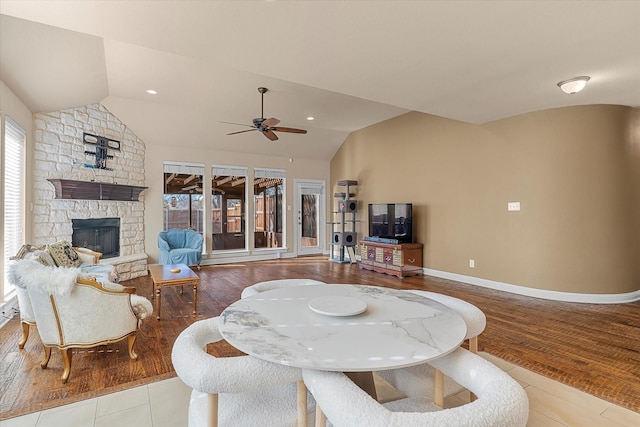 tiled living room with ceiling fan, a fireplace, and vaulted ceiling