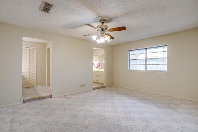 carpeted spare room with ceiling fan and a textured ceiling