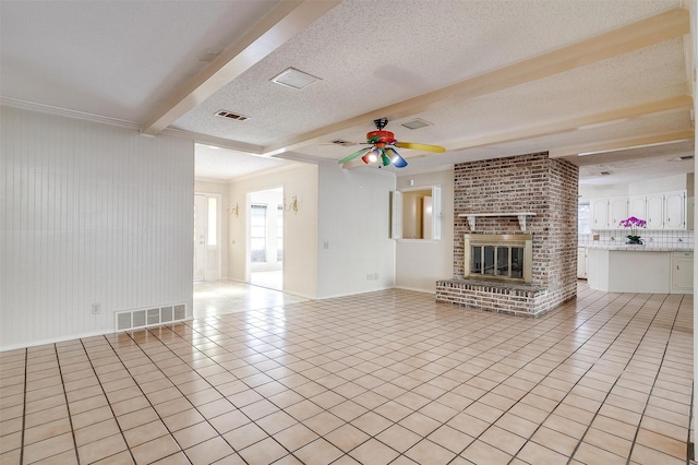 unfurnished living room with beam ceiling, ceiling fan, a textured ceiling, a fireplace, and light tile patterned flooring