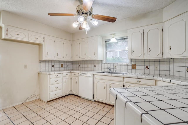 kitchen with tile countertops, backsplash, white dishwasher, sink, and white cabinetry