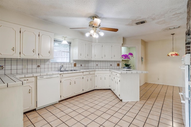 kitchen featuring white cabinetry, hanging light fixtures, tile countertops, kitchen peninsula, and white dishwasher