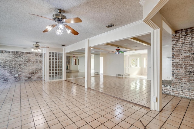 unfurnished living room with light tile patterned floors, a textured ceiling, ceiling fan, and brick wall