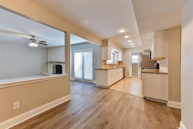 kitchen with sink, ceiling fan, light wood-type flooring, a fireplace, and white cabinetry