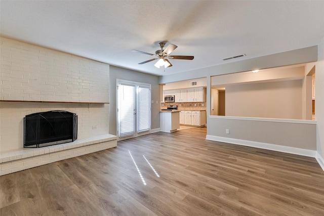 unfurnished living room with a fireplace, hardwood / wood-style flooring, and ceiling fan