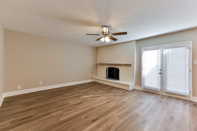 unfurnished living room with ceiling fan, a fireplace, wood-type flooring, and a textured ceiling