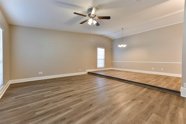 empty room featuring hardwood / wood-style floors, ceiling fan with notable chandelier, and lofted ceiling