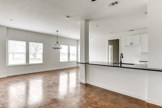 kitchen featuring sink, pendant lighting, a notable chandelier, white cabinets, and concrete floors