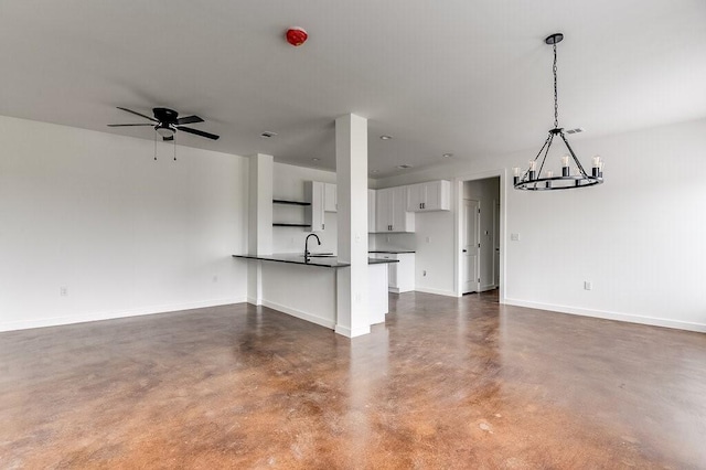 unfurnished living room with ceiling fan with notable chandelier and sink