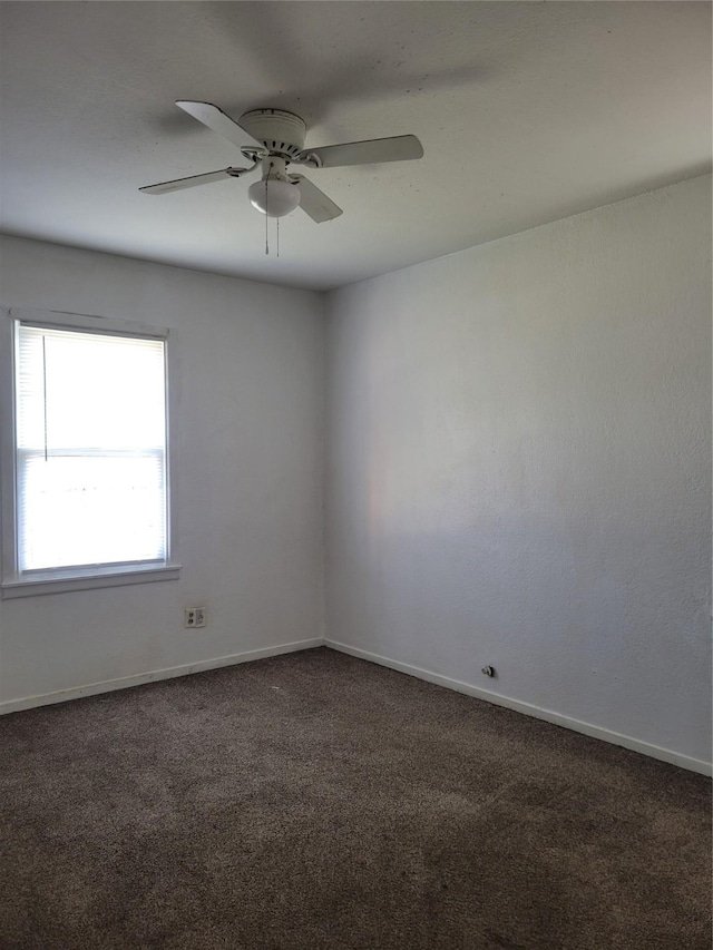 spare room with dark colored carpet and ceiling fan