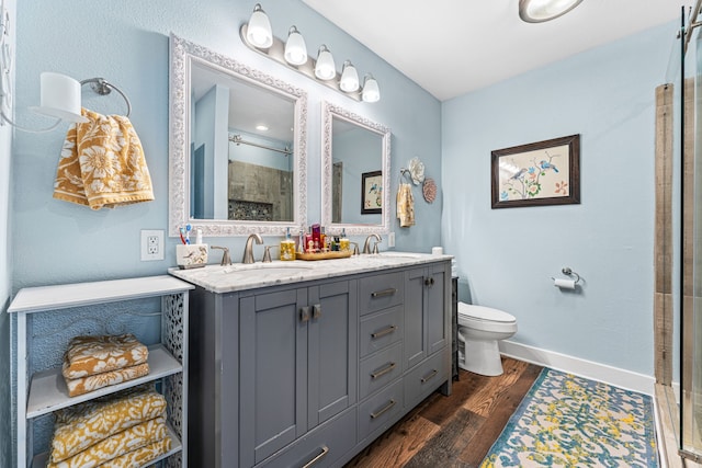 bathroom featuring hardwood / wood-style floors, vanity, toilet, and a shower with shower door