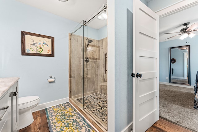 bathroom featuring vanity, hardwood / wood-style flooring, ceiling fan, toilet, and a shower with shower door