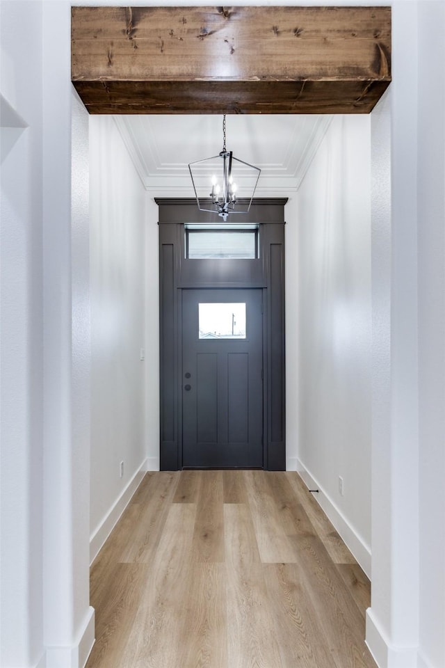 foyer featuring an inviting chandelier, baseboards, ornamental molding, and light wood finished floors