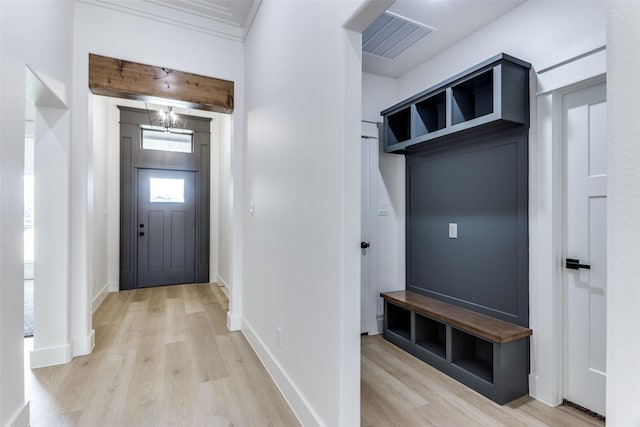 mudroom featuring light wood finished floors, baseboards, visible vents, and a notable chandelier