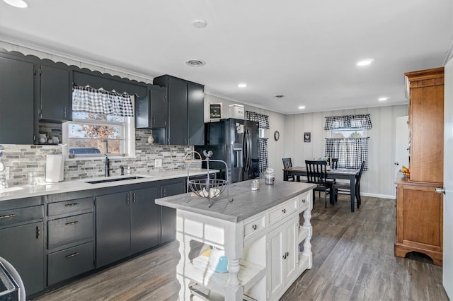 kitchen with dark hardwood / wood-style floors, black fridge with ice dispenser, sink, and a wealth of natural light