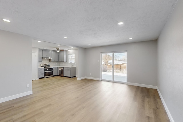 unfurnished living room featuring a textured ceiling, light wood-type flooring, and sink