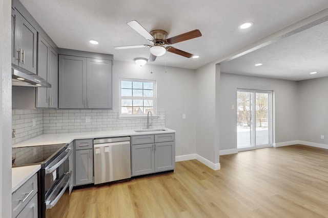 kitchen featuring backsplash, stainless steel appliances, gray cabinets, and sink