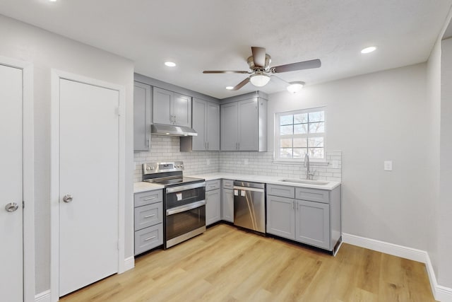 kitchen with sink, light hardwood / wood-style flooring, gray cabinets, decorative backsplash, and appliances with stainless steel finishes